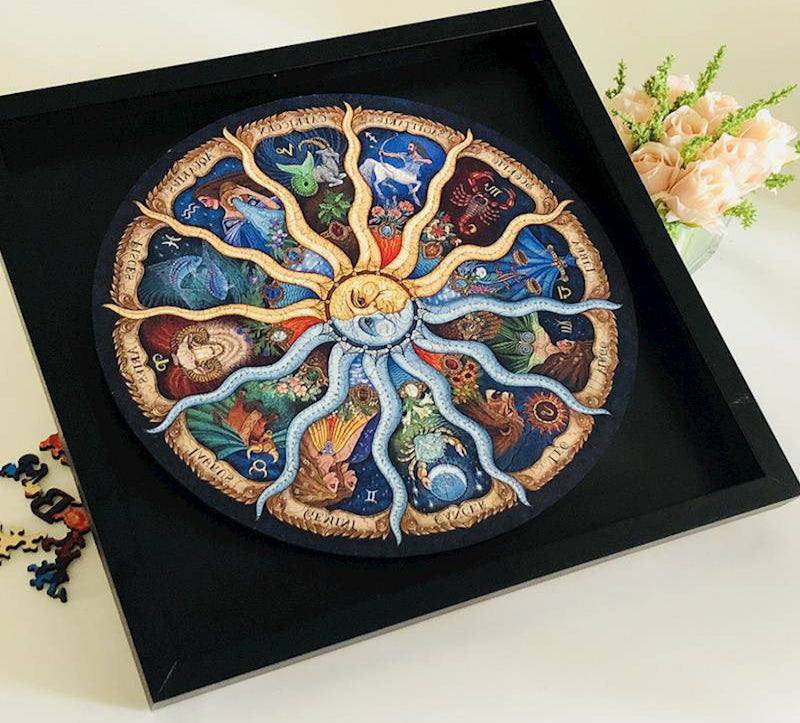 Decorative circular piece with zodiac symbols in a black frame on a light surface.