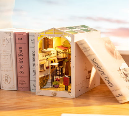 Small wooden model of a town with books titled 'Sunshine Town' on a wooden surface.