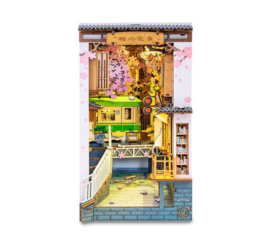 Model train set packaging with a scenic layout featuring a bridge, buildings, and cherry blossoms.