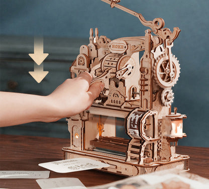 Wooden mechanical model with gears and a hand interacting with it on a wooden surface.