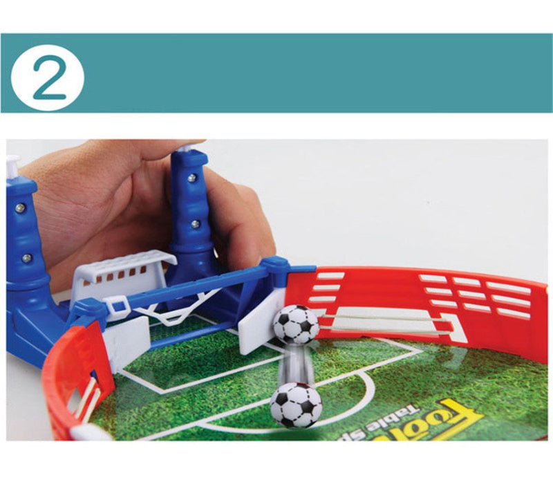 Tabletop soccer game with two goals and a ball, being held by a hand.