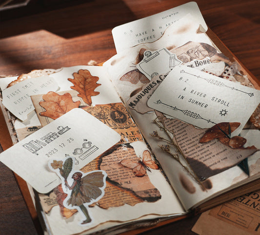 Open book with decorative stickers and paper elements on a wooden surface