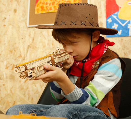 Child in cowboy costume holding a toy gun with a colorful background