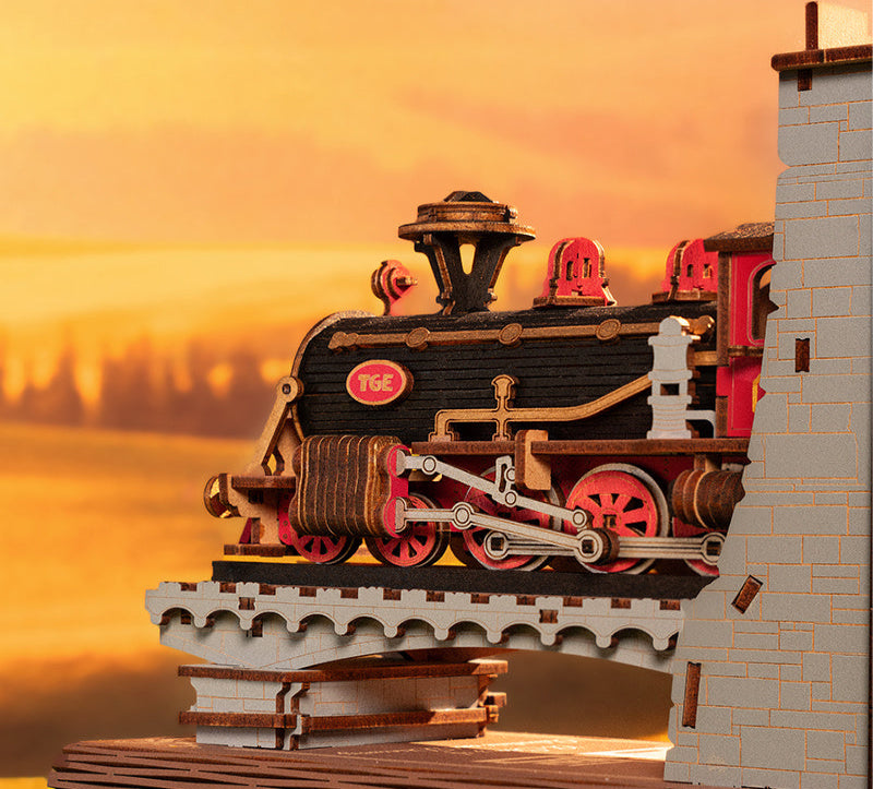 Model train on a bridge with a sunset background