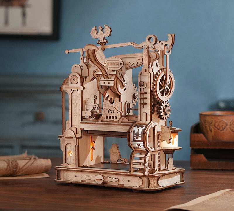 Wooden mechanical model with gears and lights on a wooden table.