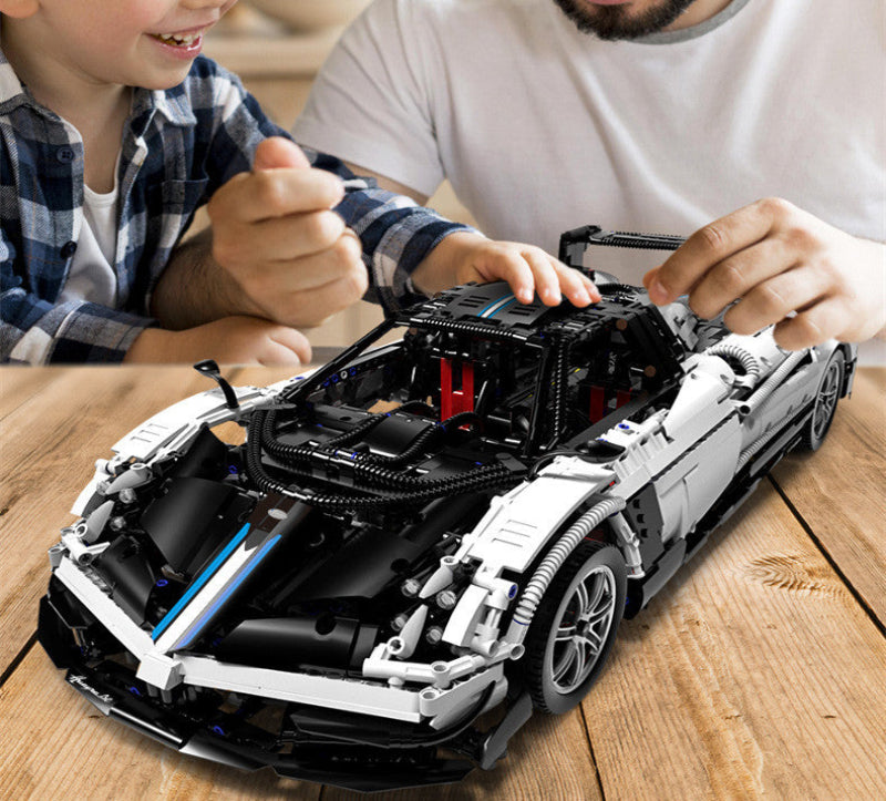 Two people working on a detailed model of a car on a wooden table