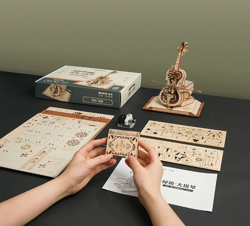 Wooden musical instrument model kit with instructions and packaging on a dark surface.
